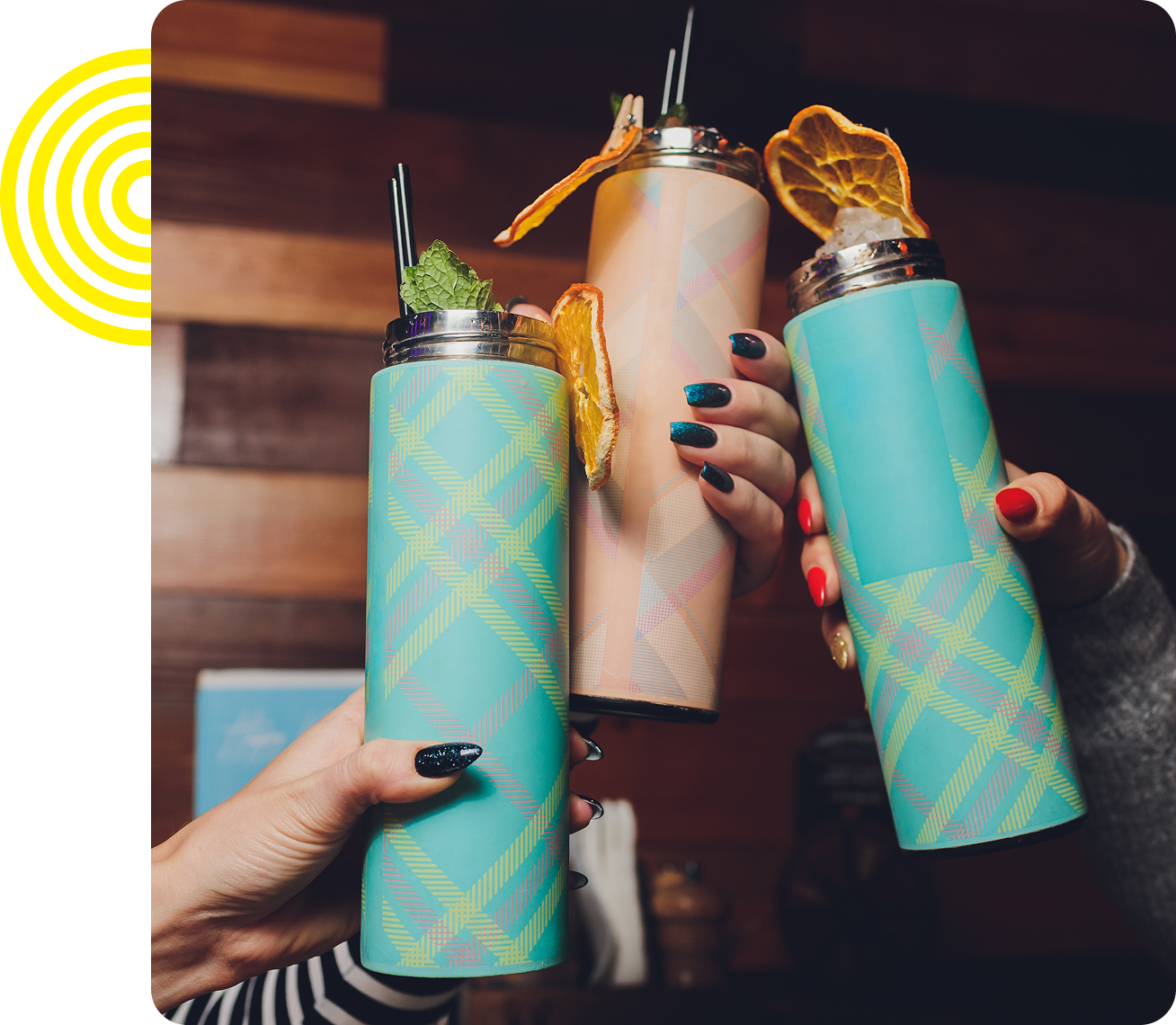 Three hands holding colorful cocktail tumblers.