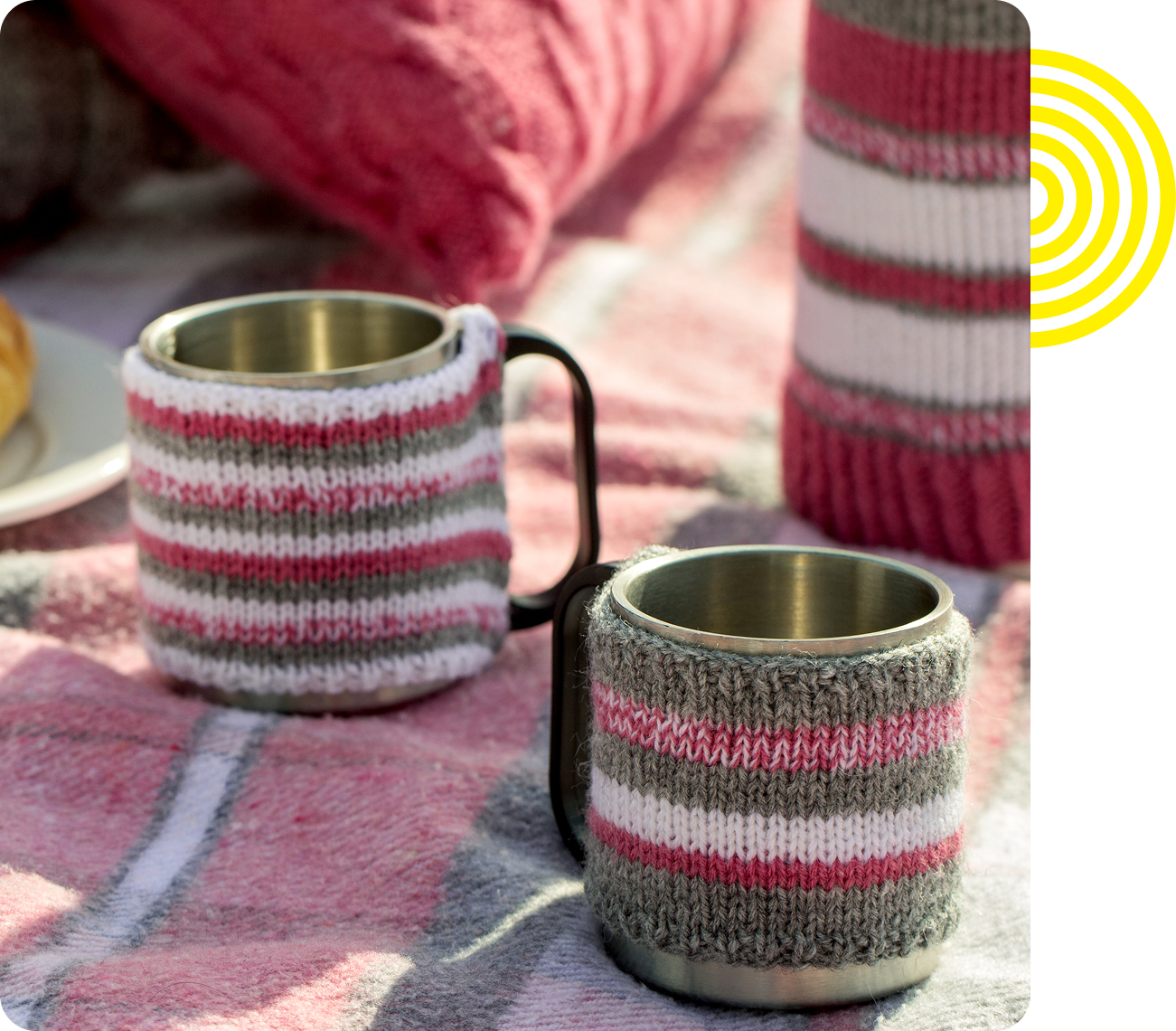 Mugs with knitted covers on blanket.
