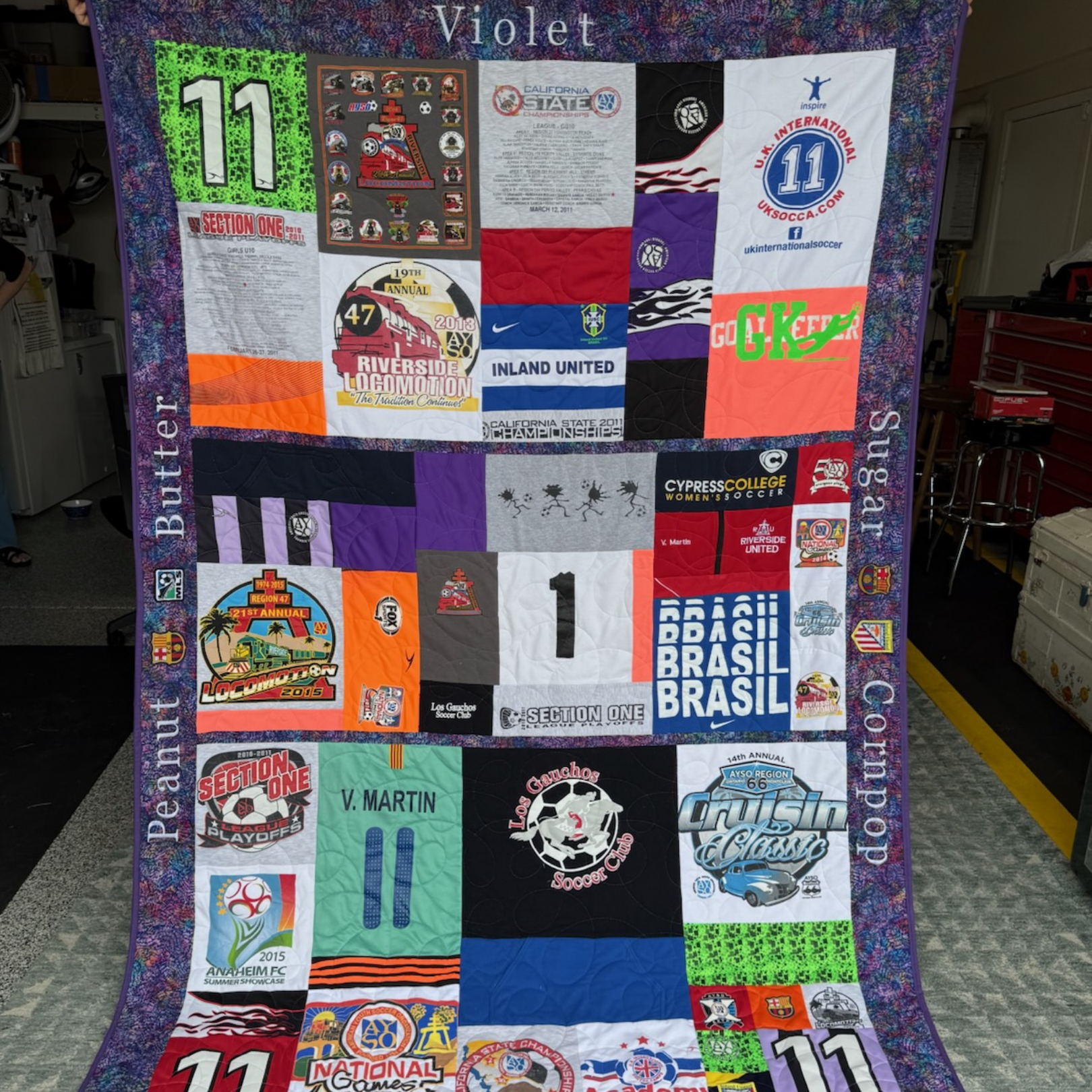 A colorful quilt made from various sports and event-themed t-shirts.